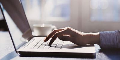 hand typing on laptop indoors